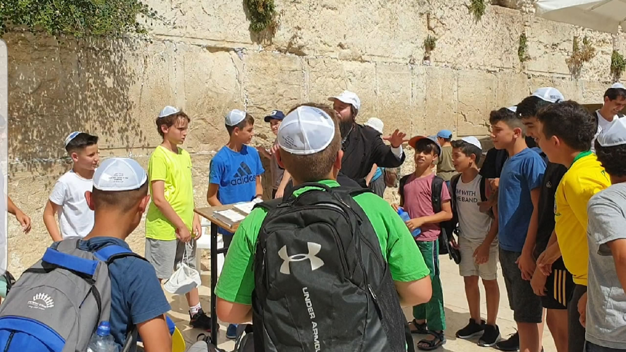 Des jeunes en voyages scolaires découvrent le mur de lamentations.